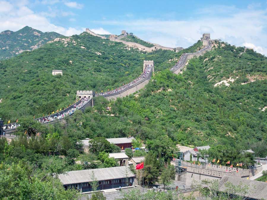 A village in the foreground, with the Great Wall, full of people, in the background.