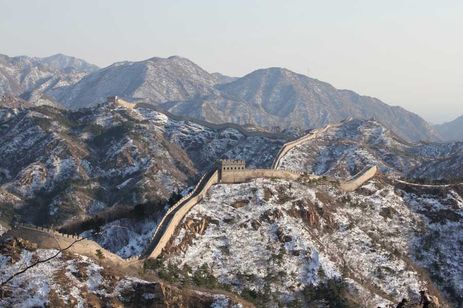 The Great Wall in winter, with the surrounding hills covered in snow.