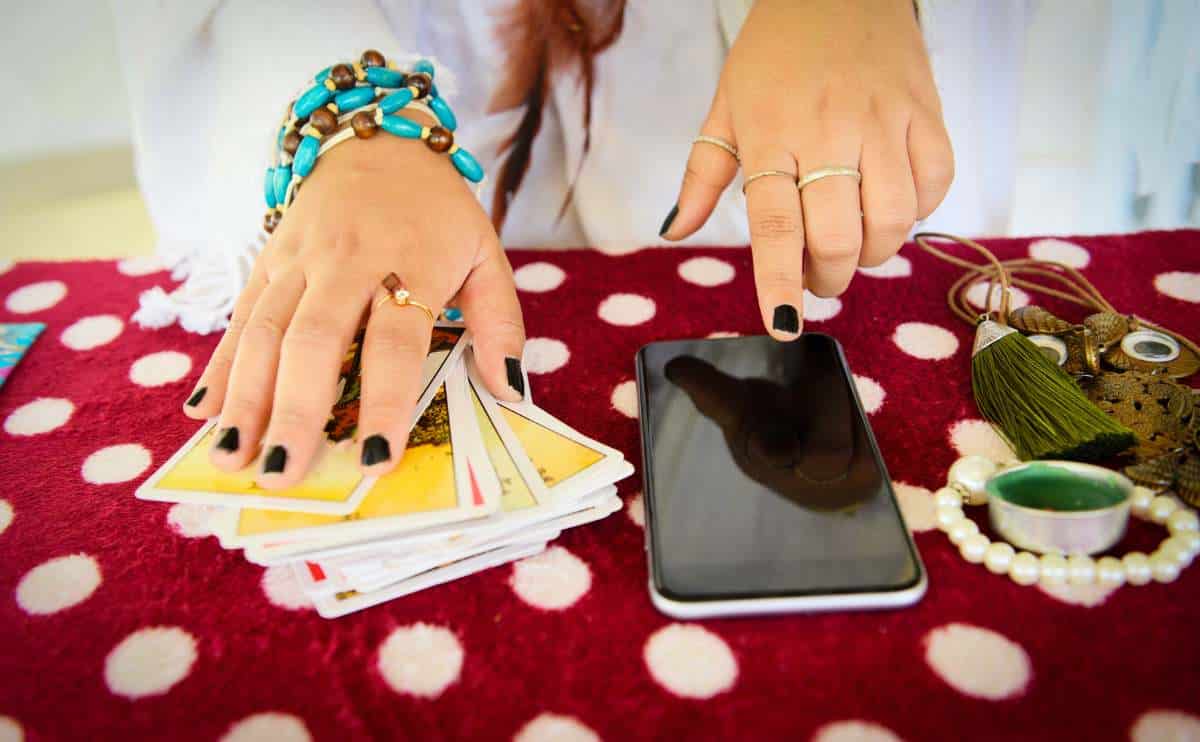 Person with tarot cards and phone conducting a psychic reading