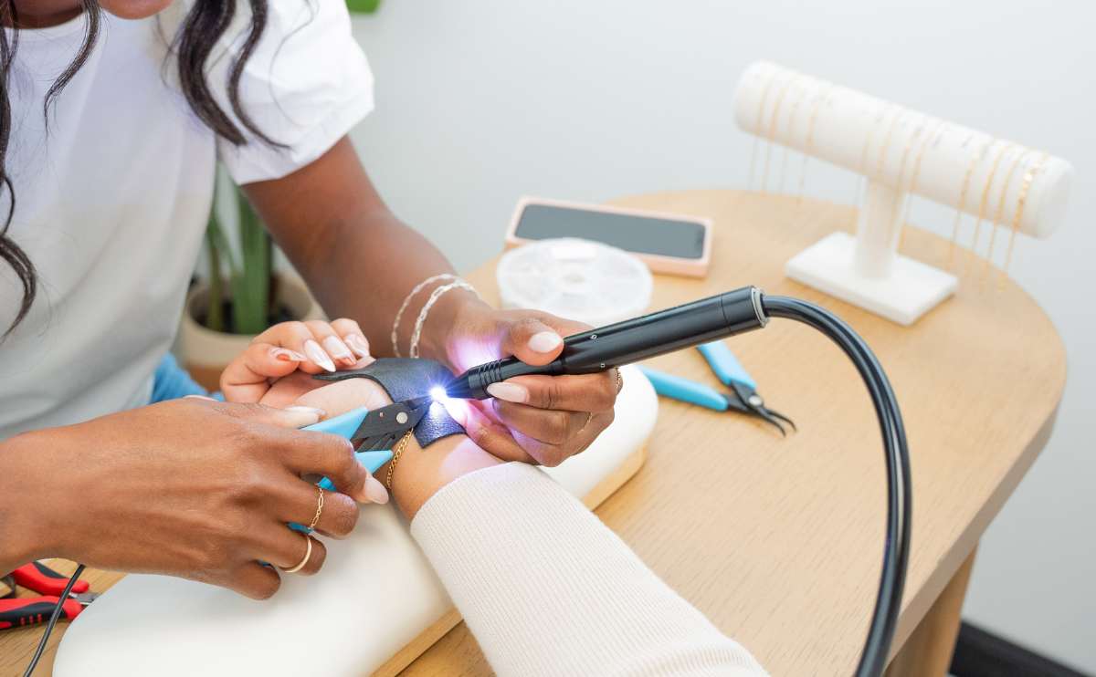 Woman welding jewelry on customer.