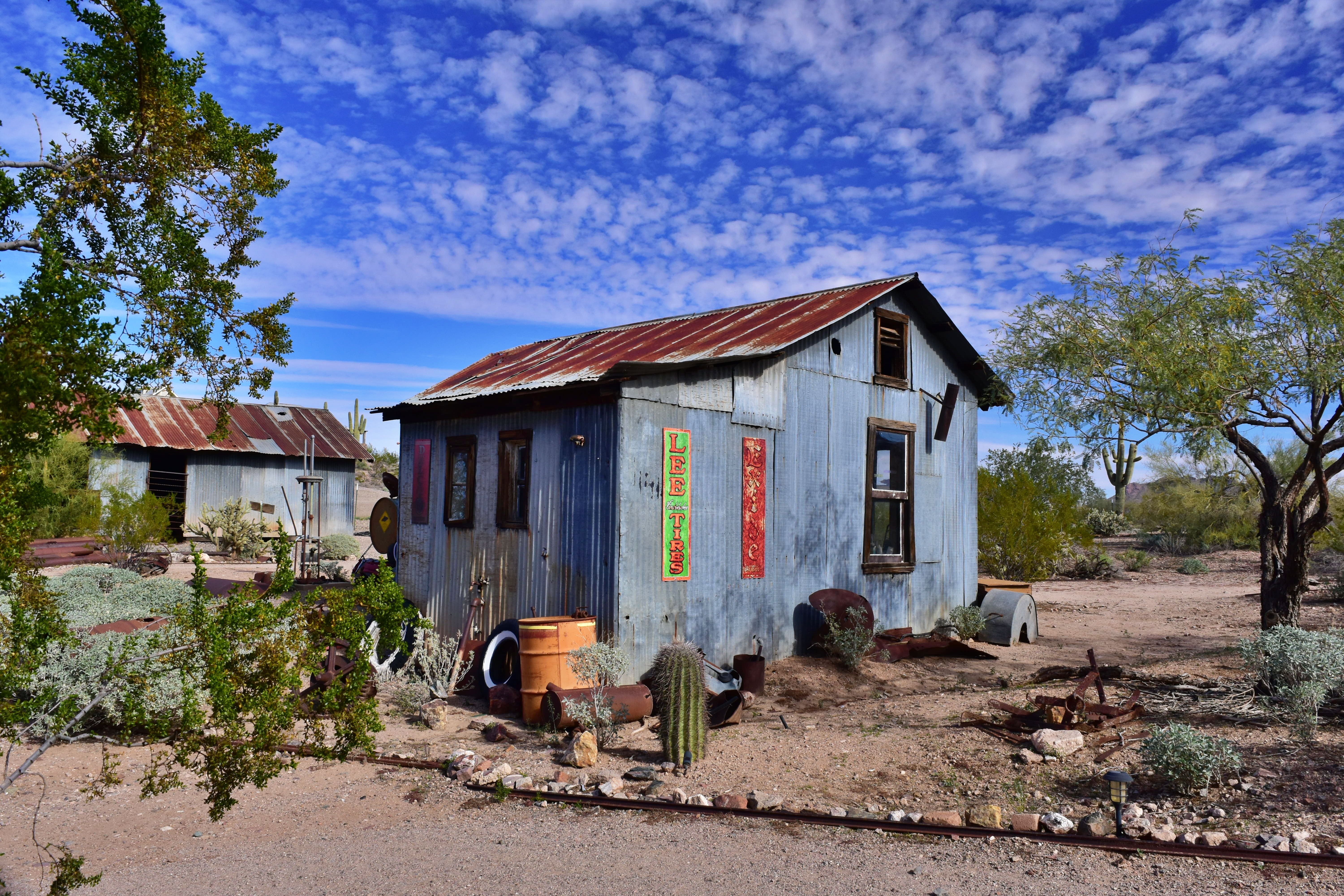 An old metal building in the Vulture City Ghost town located in Wickenbury, AZ against the blue sky and clouds.