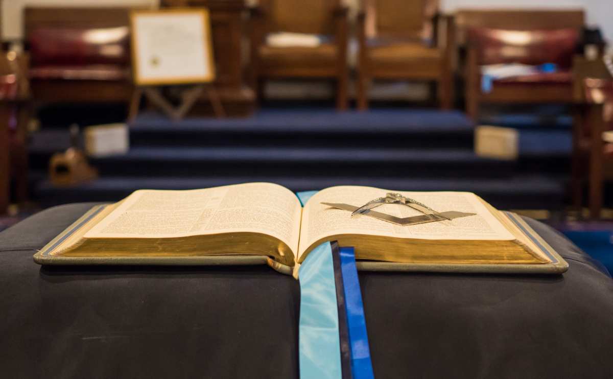 Freemasonry compasses and bible laid open on table.