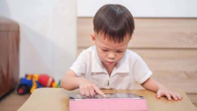 Young child with autism using an autism app on an ipad with a pink cover